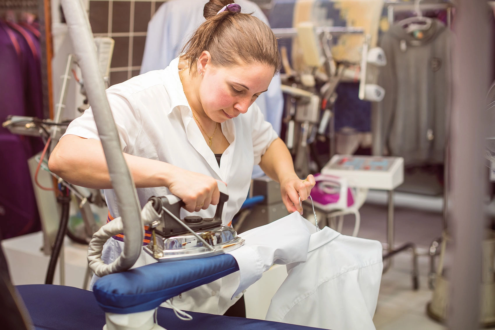 Femme repassant un vêtement avec un linge blanc pour tester si la couleur déteint
