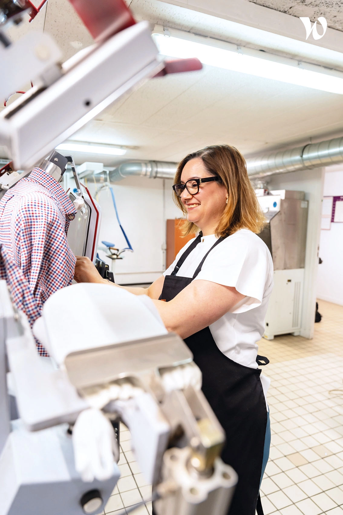 Employée en formation pressing professionnel utilisant une machine de repassage en atelier